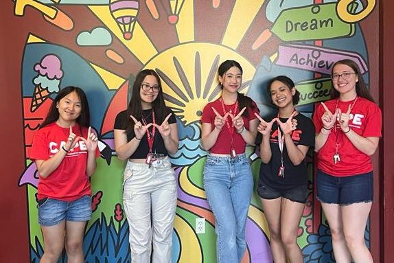 CAPE students posing in front of a mural