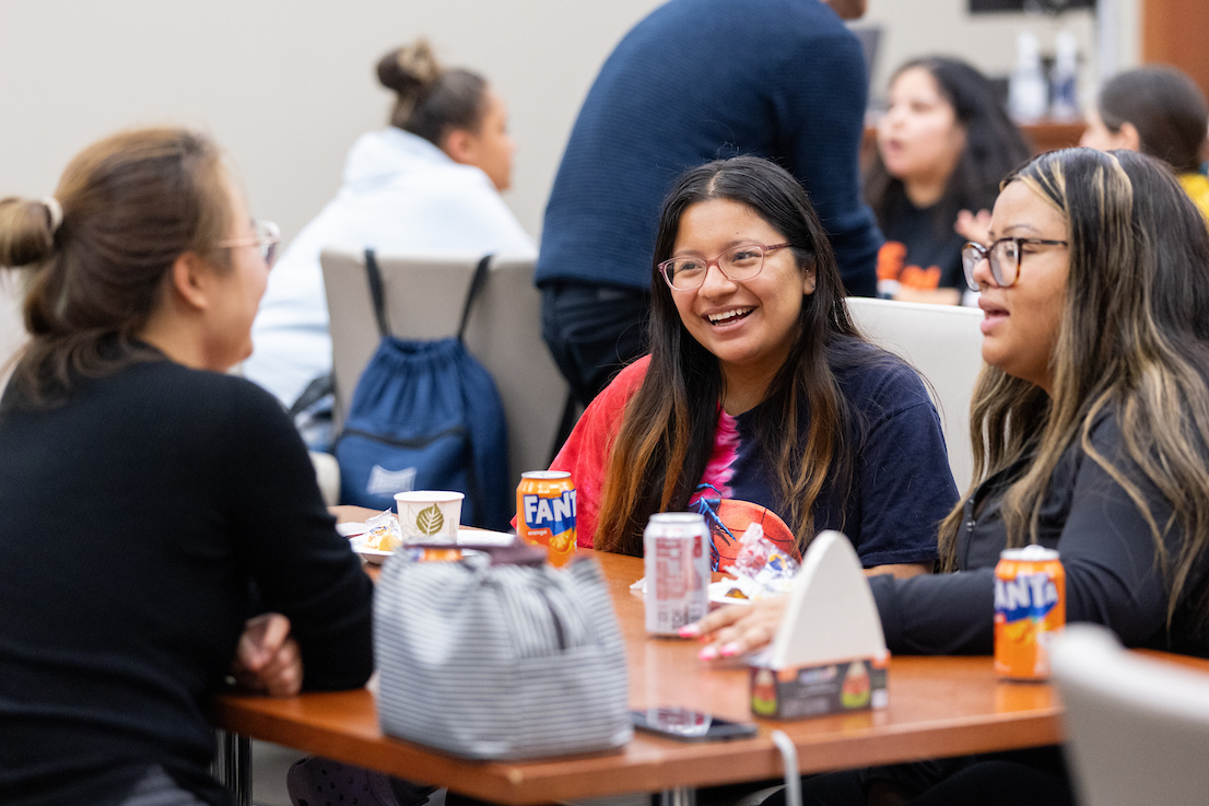 Three students smiling at a table.