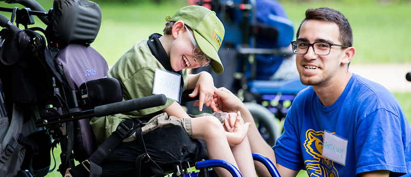 Volunteer interacts with child in wheelchair at event