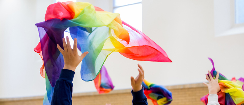 People in movement class throwing colorful scarves in the air
