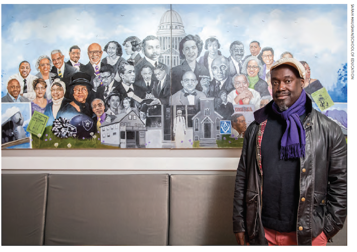 Jerry Jordan standing by a mural depicting African-American history