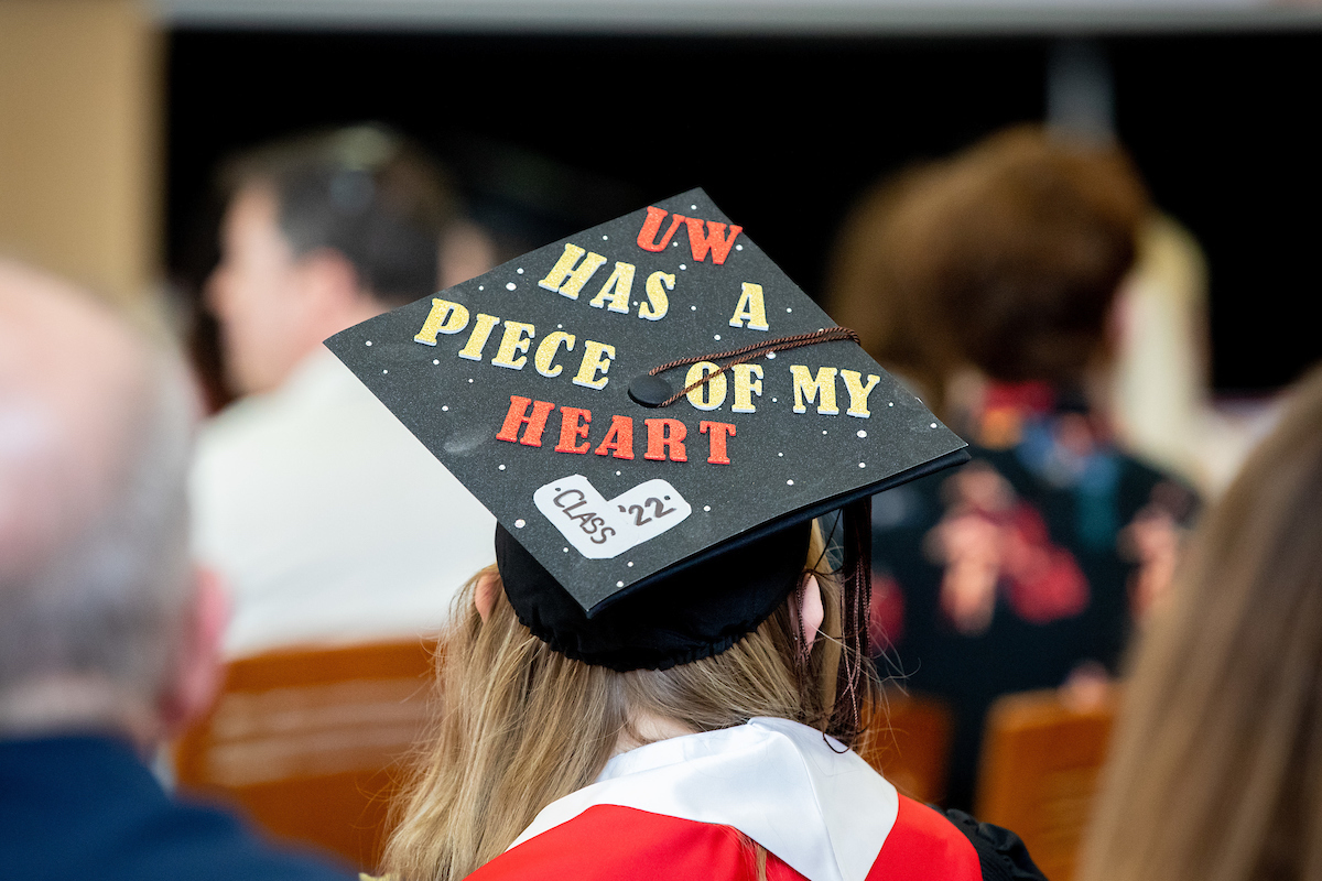 Graduating student in commencement hat that says, 