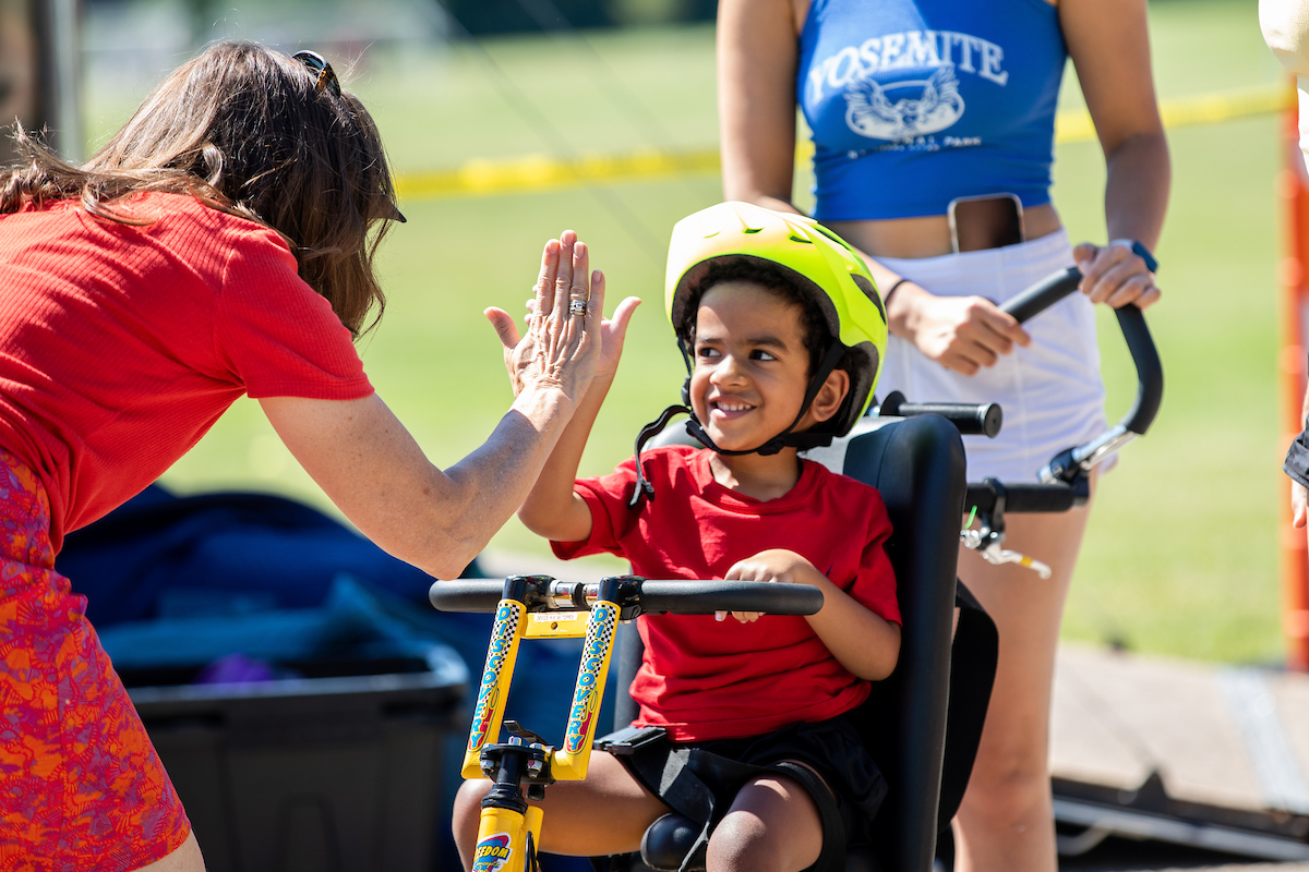 Child in No Limit Kids Fitness program using an adapted bike, getting a 