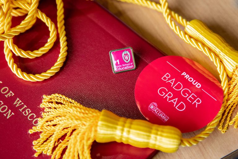 uw-madison diploma beneath tassels, pin, and button saying proud badger grad