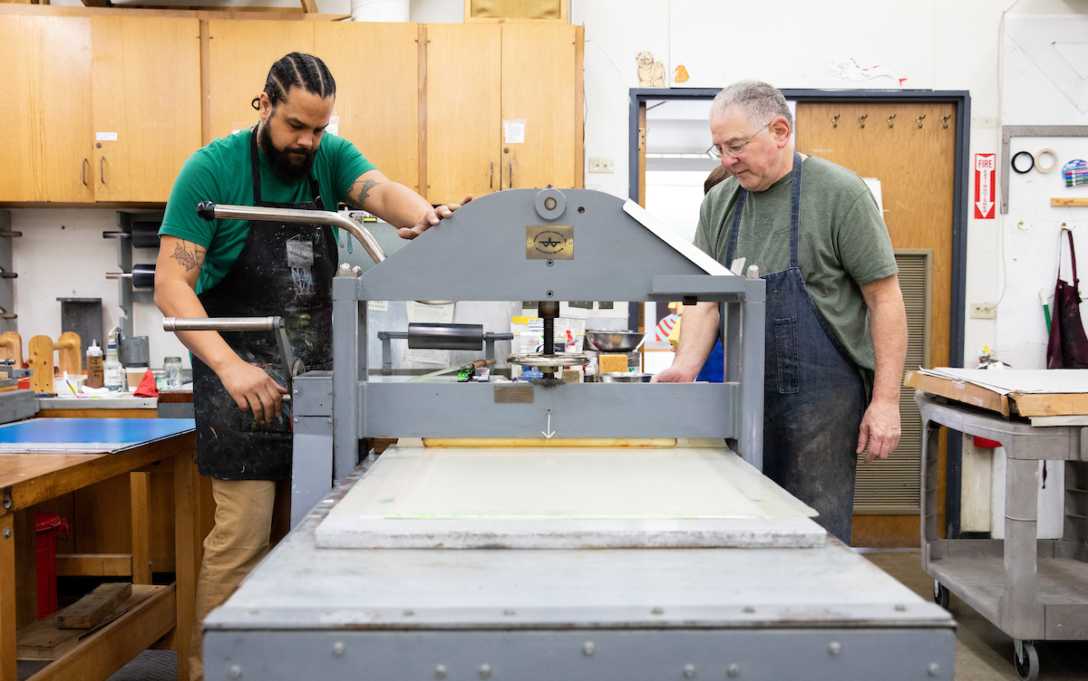 Printmaking Professor Andy Rubin and guest printmaker Aaron Coleman work on a litho print together.