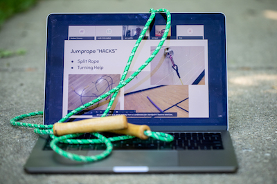 Laptop outside on the ground with a jump rope laying on top of it