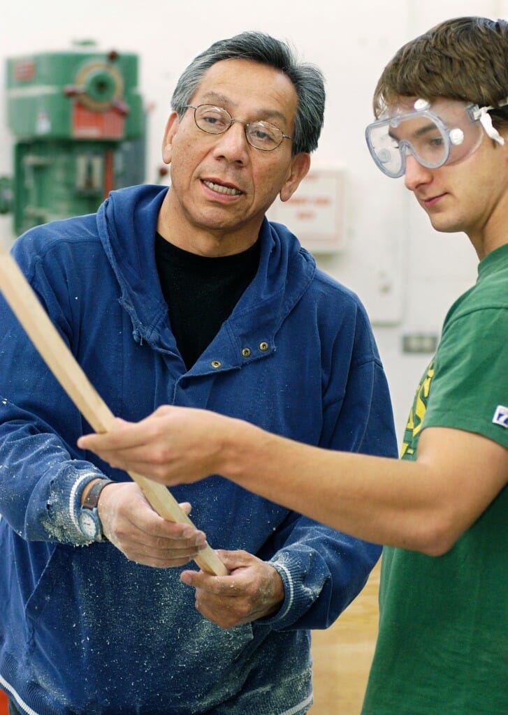 Truman Lowe, professor of art and a wood sculptor, teaches a student how to safely use a table saw and offers other woodworking tips during a wood sculpture class in 2004.