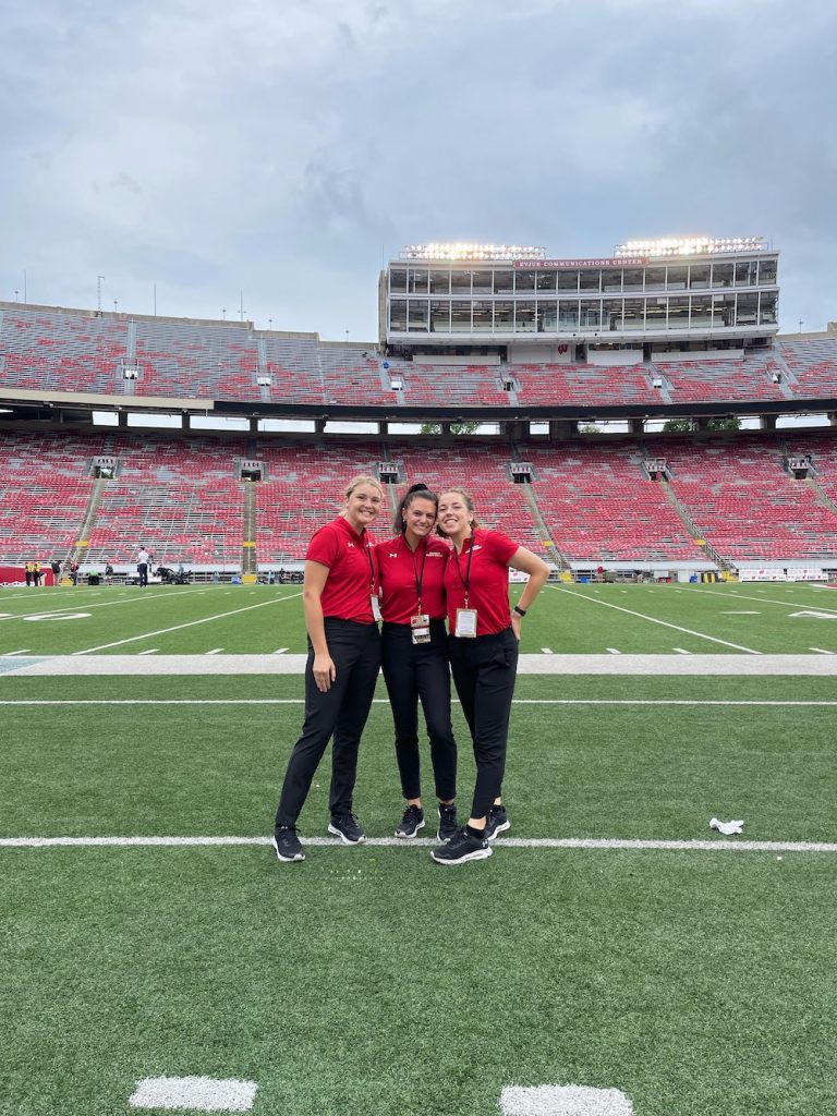 Erin Malec and two other people standing on a football field.