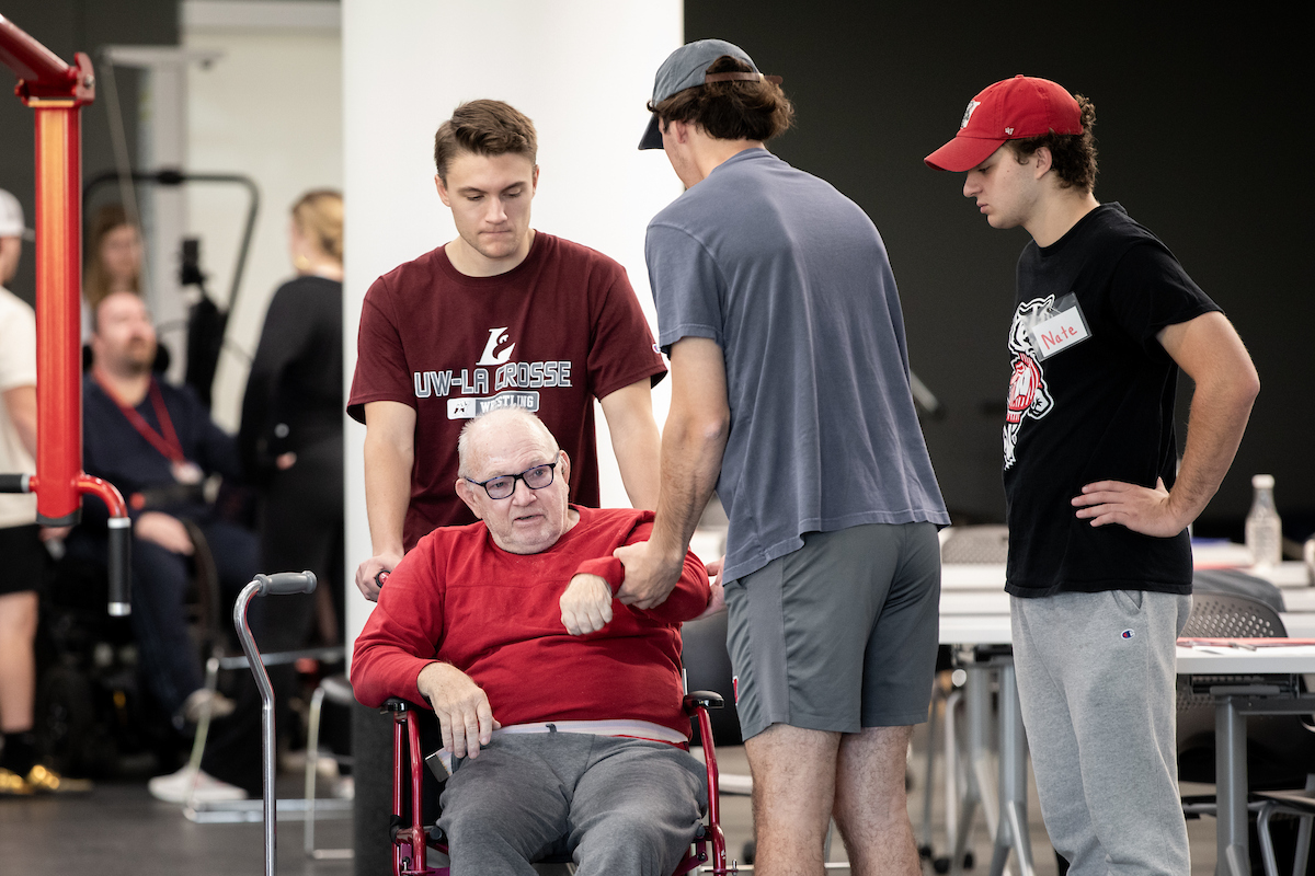 college students work with a man in a wheel chair