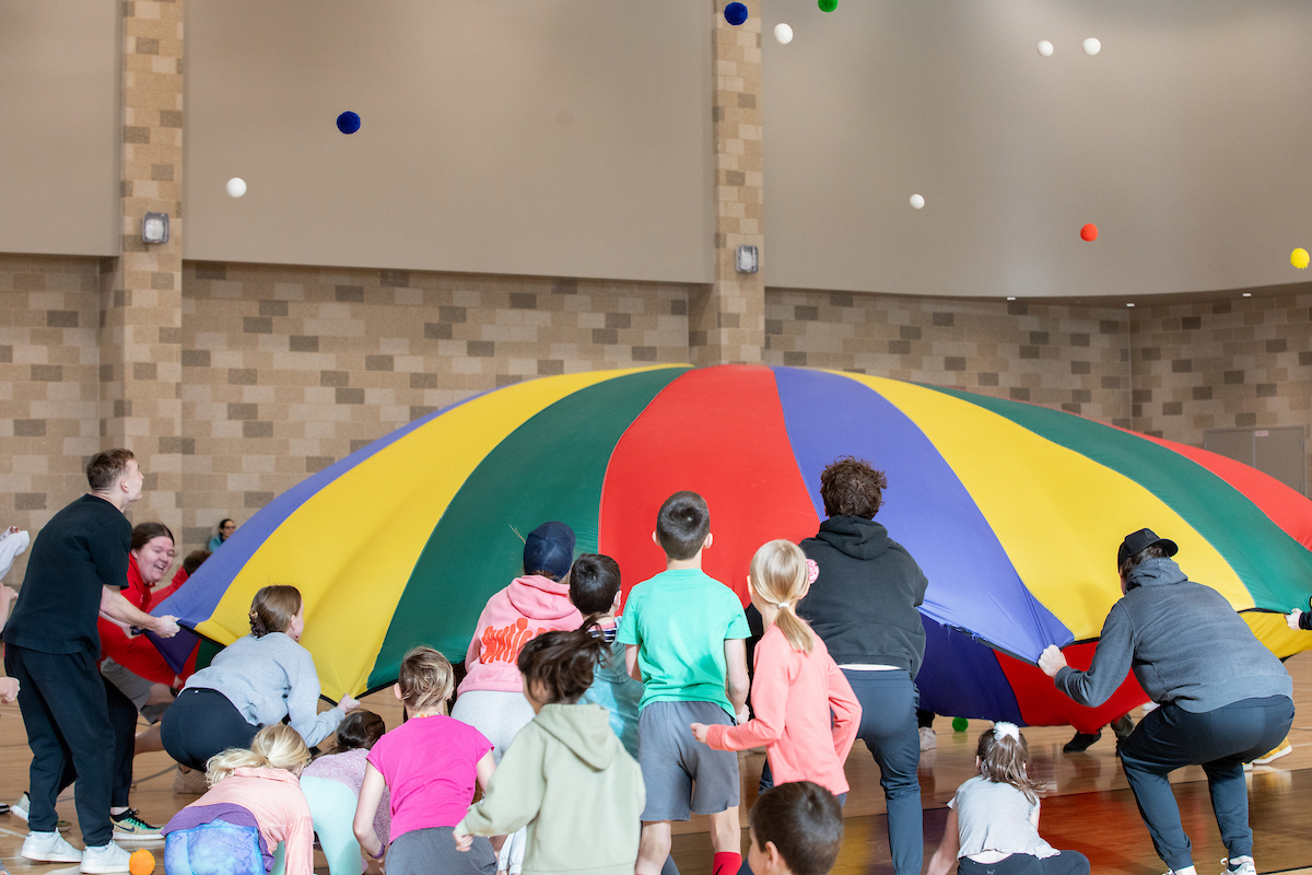 college students work with children in a physical education class