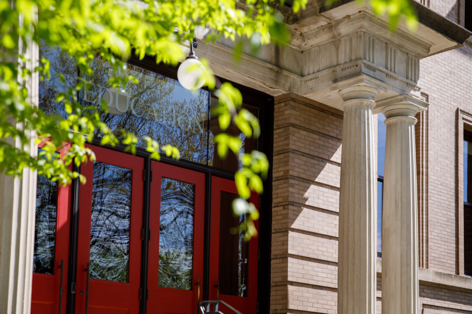 the front doors of the education building with a tree in the forground