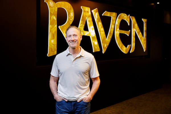 Brian Raffel standing in front of Ravensoft logo