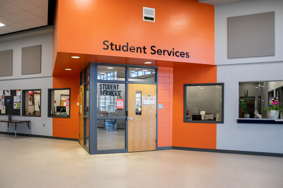 lobby area of a high school and a sign that says student services.