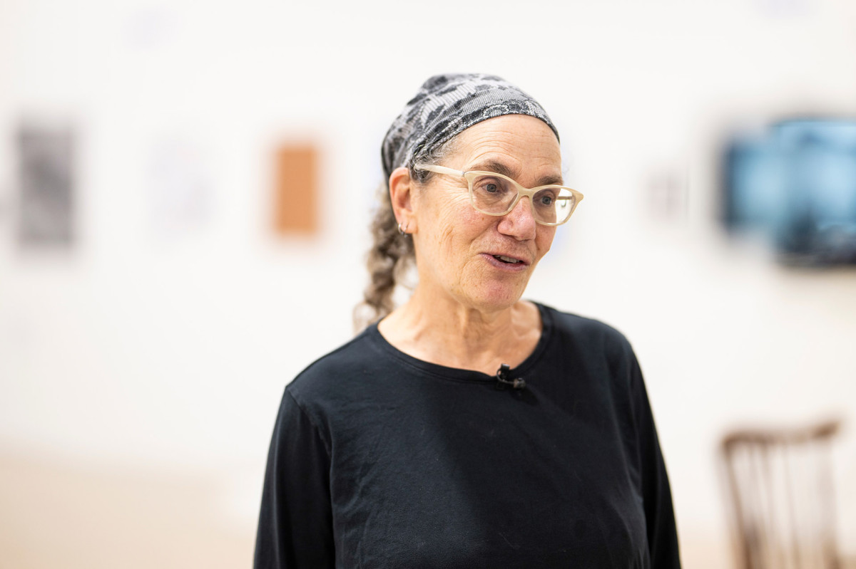 Laurie Beth Clark wearing a bandana on her head in the gallery space