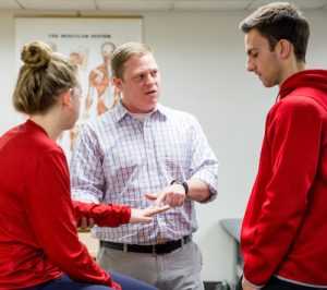 Faculty member David Bell teaches two students in an athletic training class.