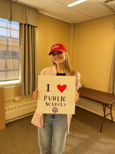Lily Bauer smiling with an "I love public schools" sign.