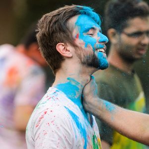 male student with blue chalked face smiles during the festival of colors, an Indian tradition