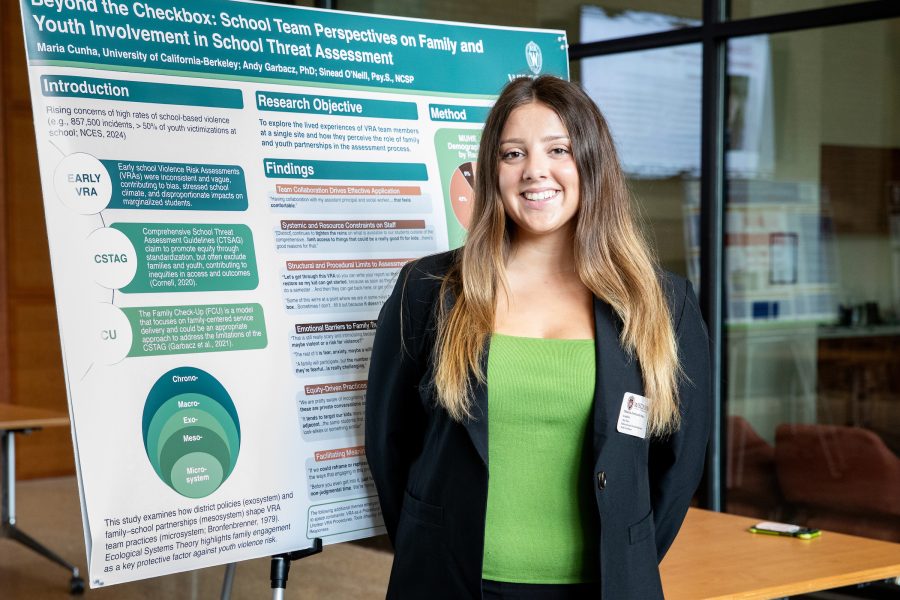 Maria Fernanda Souza Cunha stands next to a SERP research poster.