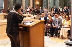 man speaks from podium in front of crowd