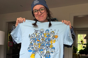 woman holds a blue t-shirt with a baseball theme