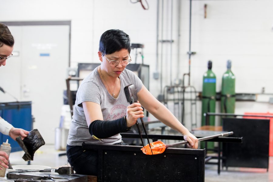 a person sitting in a chair working with melted glass